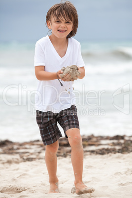 cute little boy playing in sand on beach in summer