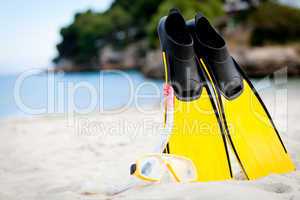 yellow fins and snorkelling mask on beach in summer