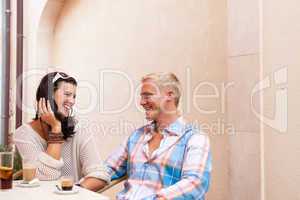 happy young couple sitting outside cafe restaurant drinking coffee