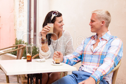 happy young couple sitting outside cafe restaurant drinking coffee