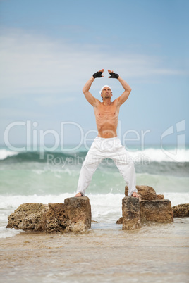 healthy man doing pilates yoga meditation on beach summer