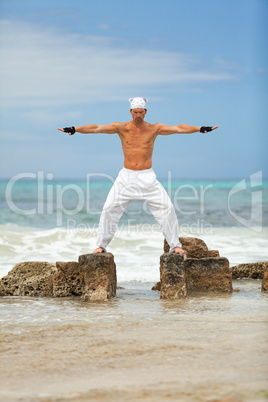 healthy man doing pilates yoga meditation on beach summer