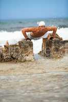 healthy man doing pilates yoga meditation on beach summer