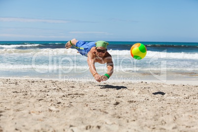 attractive adult man playing beach volleyball in summer