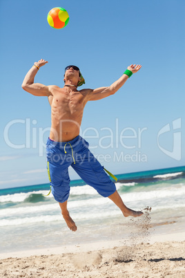 attractive young man playing volleyball on the beach