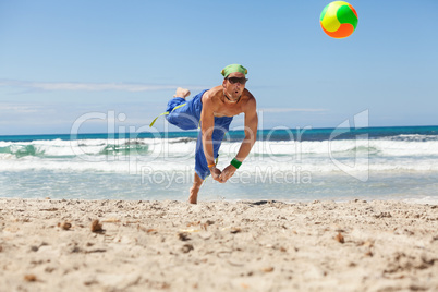 attractive young man playing volleyball on the beach