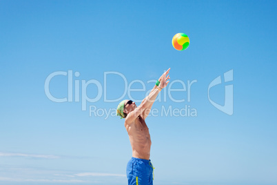 attractive young man playing volleyball on the beach