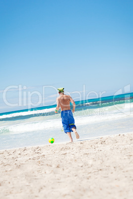 attractive young man playing volleyball on the beach