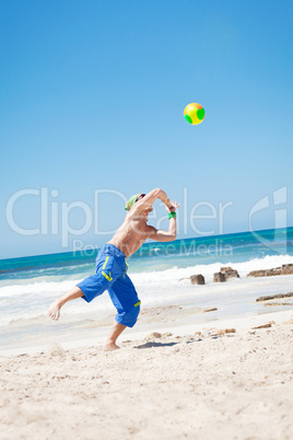 attractive young man playing volleyball on the beach