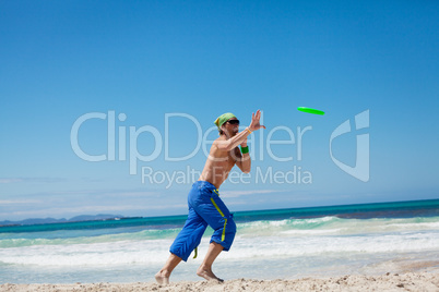 attractive man playing frisby on beach in summer