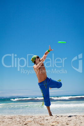 attractive man playing frisby on beach in summer