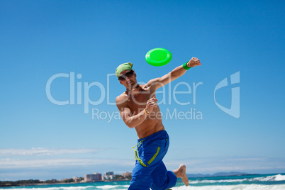 attractive man playing frisby on beach in summer