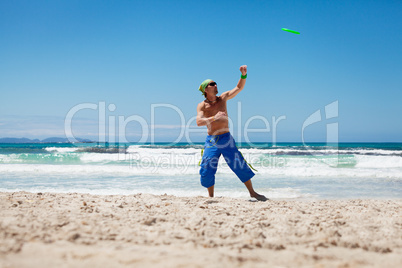 attractive man playing frisby on beach in summer