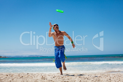 attractive man playing frisby on beach in summer