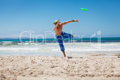 attractive man playing frisby on beach in summer
