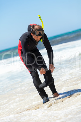 male diver with diving suit snorkel mask fins on the beach