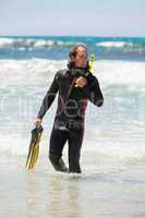 male diver with diving suit snorkel mask fins on the beach