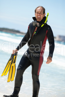 male diver with diving suit snorkel mask fins on the beach