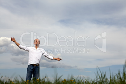 man is standing outside in spring with arms wide open and breathing