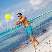 happy young adult man playing beach ball in summer
