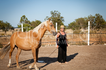 young woman training horse outside in summer