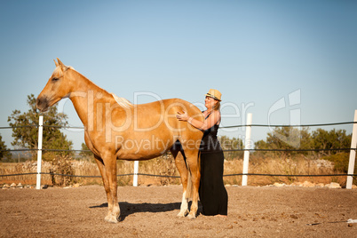 young woman training horse outside in summer