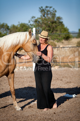 young woman training horse outside in summer