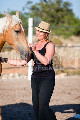 young woman training horse outside in summer