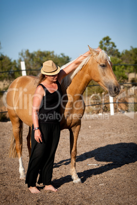 young woman training horse outside in summer