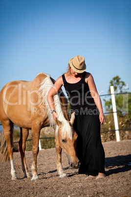 young woman training horse outside in summer