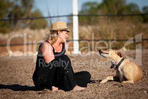 smiling blonde woman sitting outdoor with her dog
