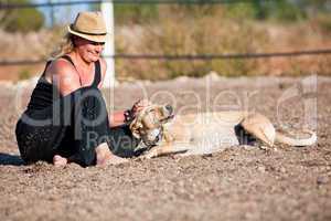 smiling blonde woman sitting outdoor with her dog