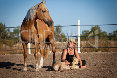 young woman training horse outside in summer