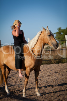 young woman training horse outside in summer