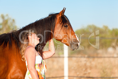 young woman training horse outside in summer