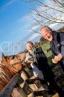 Elderly couple petting a horse in a paddock