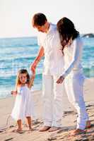 happy young family with daughter on beach in summer