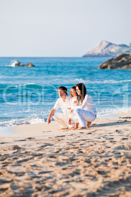 happy young family with daughter on beach in summer