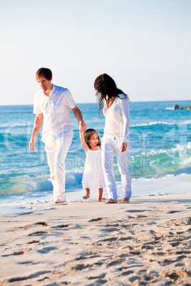 happy young family with daughter on beach in summer