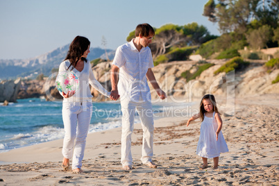 happy young family with daughter on beach in summer