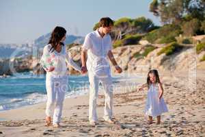 happy young family with daughter on beach in summer