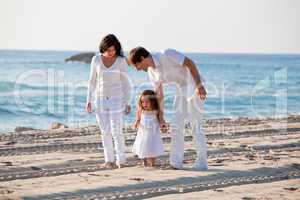 happy young family with daughter on beach in summer