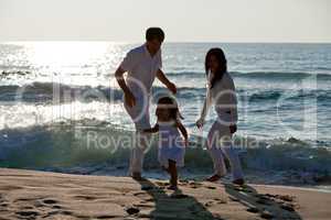 happy young family with daughter on beach in summer