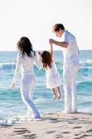 happy young family with daughter on beach in summer