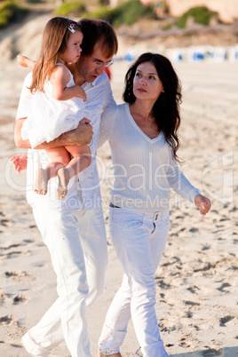 happy young family with daughter on beach in summer