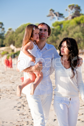 happy young family with daughter on beach in summer