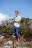 young man outside in summer on beach with mobile phone