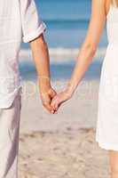couple in love hand in hand on beach in summer