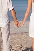 couple in love hand in hand on beach in summer