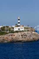 white lighthouse on rocks in the sea ocean water sky blue